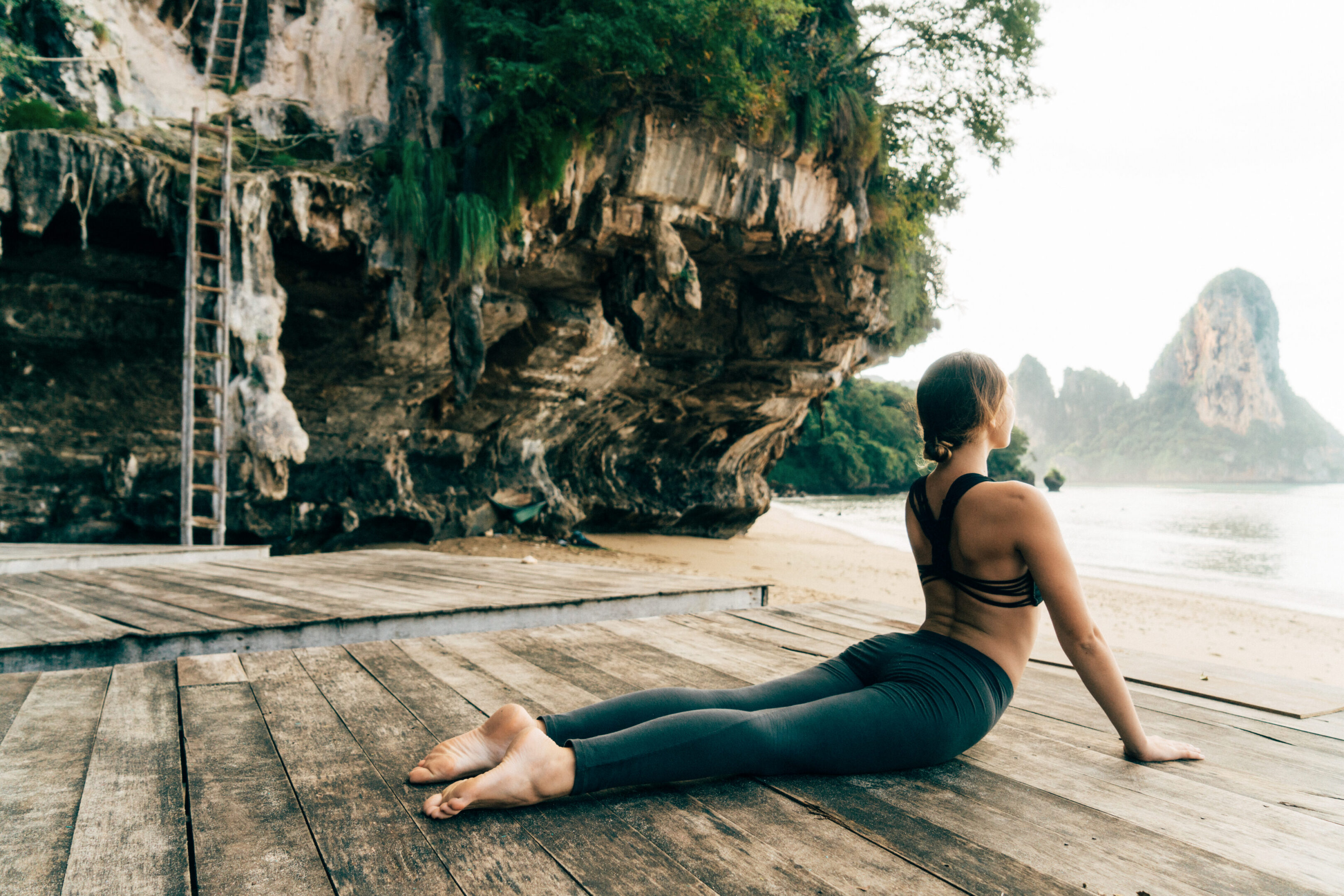 Woman practicing yoga by the ocean